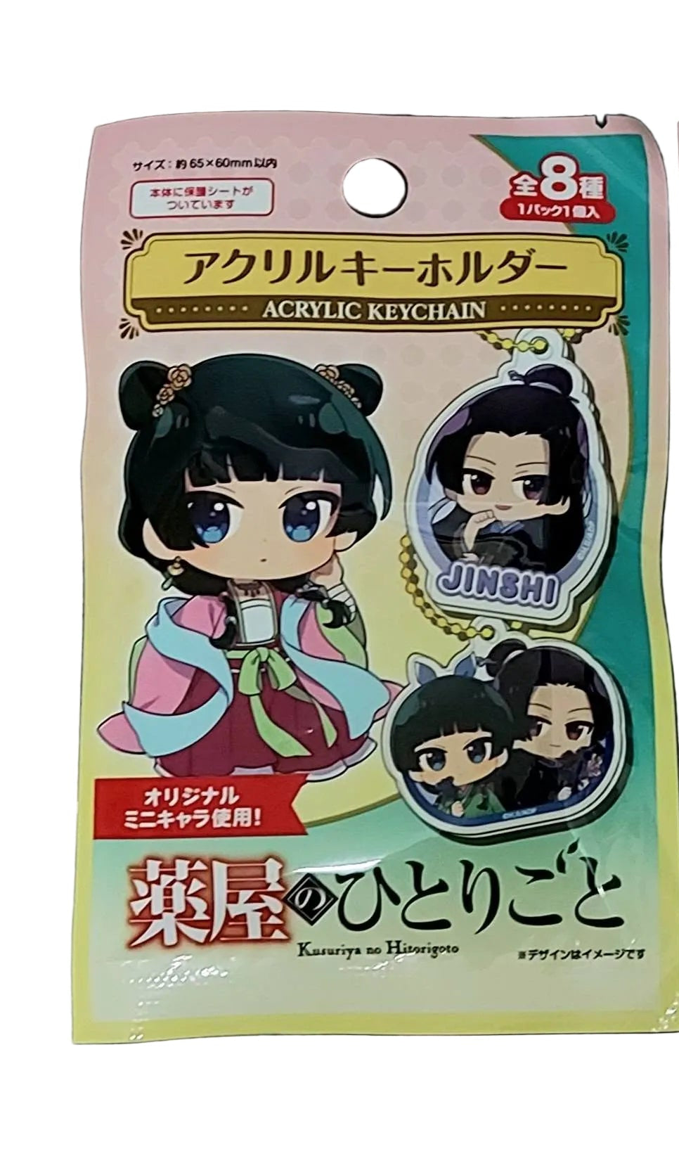 Two packages of anime character keychains on a gray surface