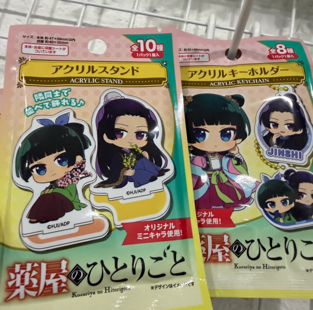 Two packaged anime acrylic stand and keychain products with Japanese text, featuring chibi character designs on colorful backing cards.